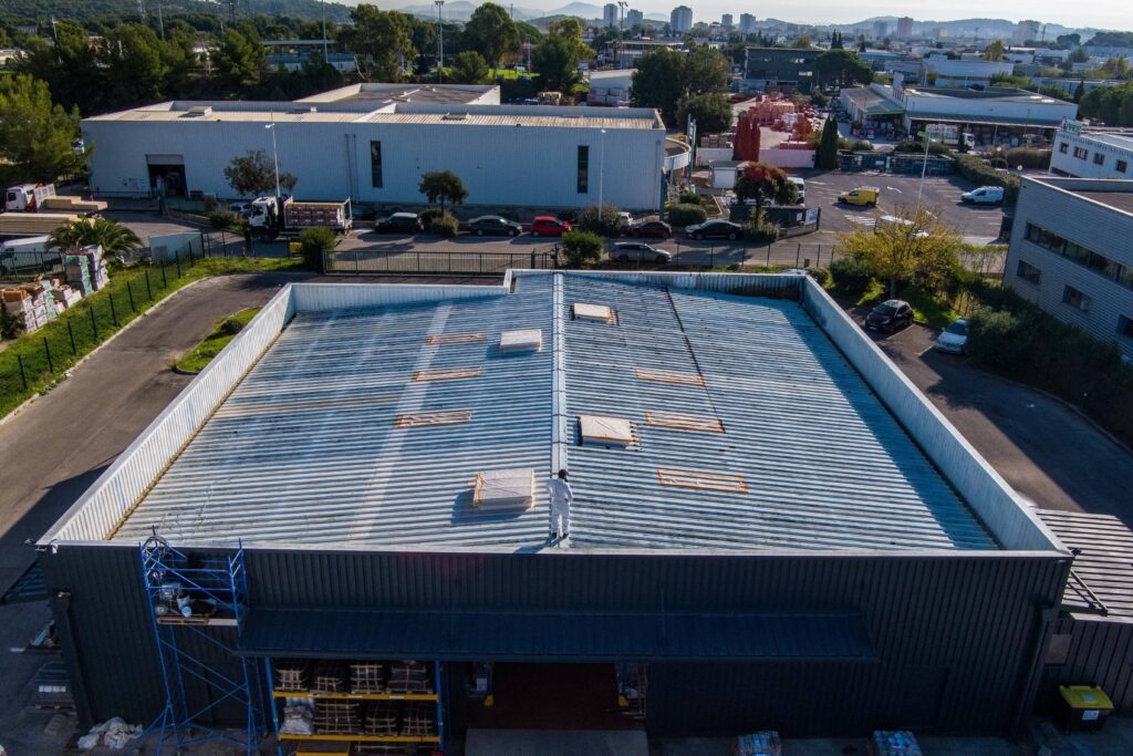 Vue aérienne d'une toiture traitée en cool roofing sur un bâtiment industriel, illustrant les avantages de la toiture froide.